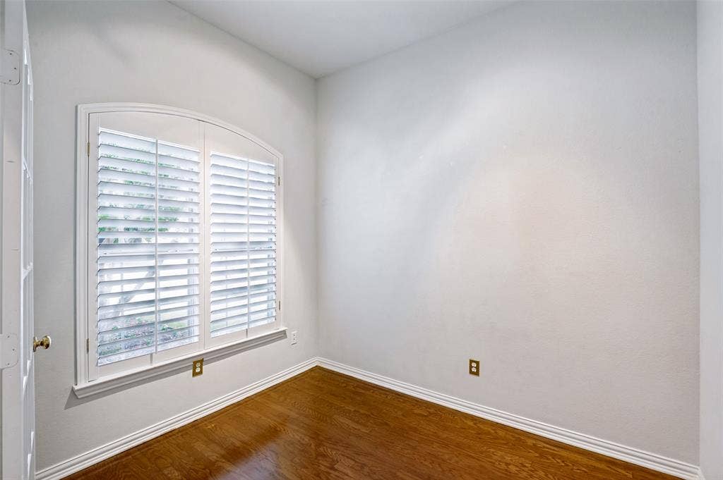 8012 Springmoss Drive, Plano, TX 75025 Room featuring an arched window with plantation shutters, wood-finish flooring, and white baseboards