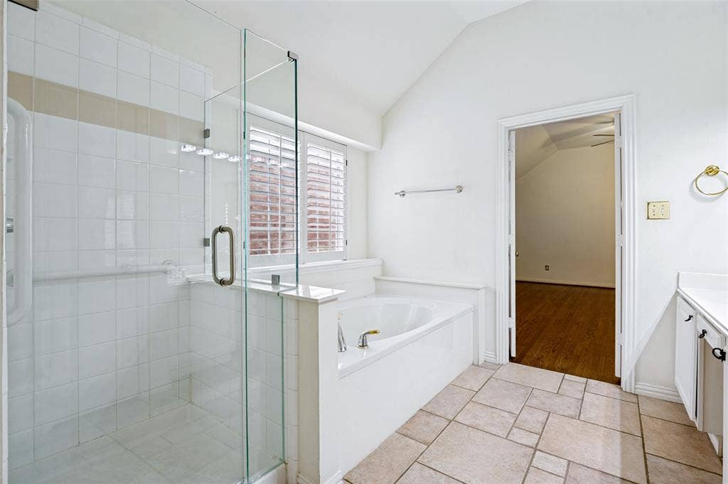 8012 Springmoss Drive, Plano, TX 75025 Bathroom featuring a glass-enclosed shower, a built-in tub with deck, white cabinetry, and a vanity with an integrated sink