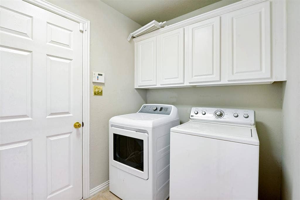 8012 Springmoss Drive, Plano, TX 75025 Laundry area featuring overhead white paneled cabinetry, light neutral wall paint, and light-toned flooring