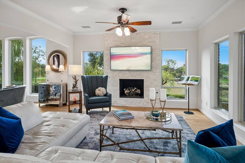 7501 Sweetgum Drive, Irving, TX 75063 Living area with light wood-finish flooring, a stone-clad fireplace, and a ceiling fan