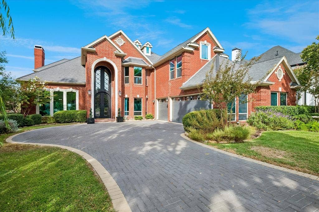 7501 Sweetgum Drive, Irving, TX 75063 Brick facade exterior with a gabled roofline, arched entry, paver driveway, and an attached garage