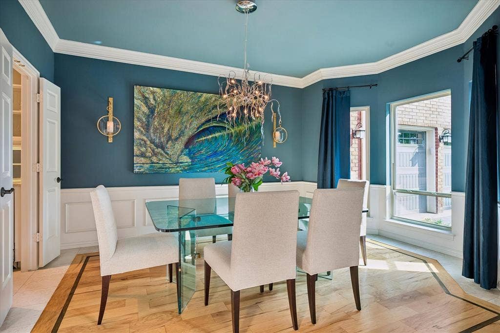 7501 Sweetgum Drive, Irving, TX 75063 Wainscoting and crown molding details, wood flooring with a decorative border, modern chandelier, and multiple windows