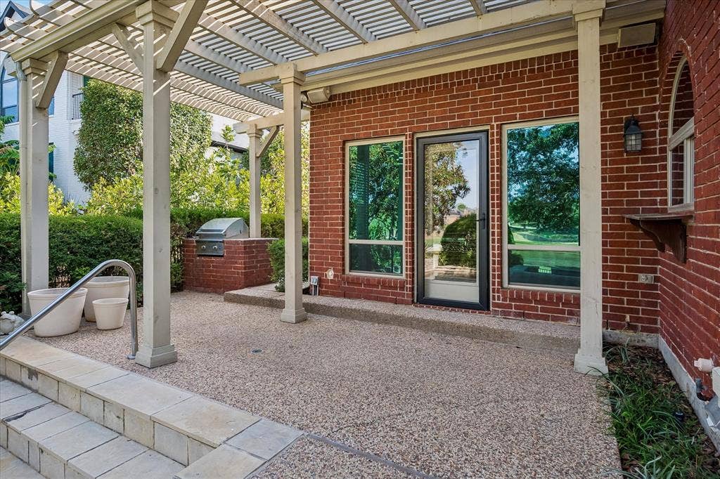 7501 Sweetgum Drive, Irving, TX 75063 Exposed aggregate patio with a built-in outdoor grill, a white pergola structure, and red brick exterior