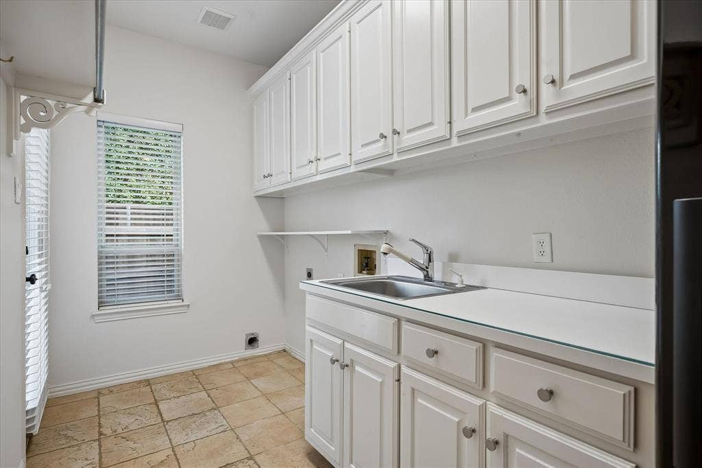 7501 Sweetgum Drive, Irving, TX 75063 Laundry area featuring built-in cabinetry, a utility sink, and tiled flooring