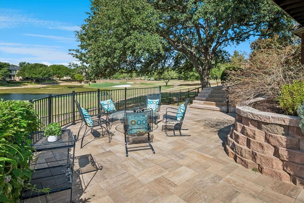 7501 Sweetgum Drive, Irving, TX 75063 Paved patio with a black metal fence, stone retaining wall, and integrated stone steps
