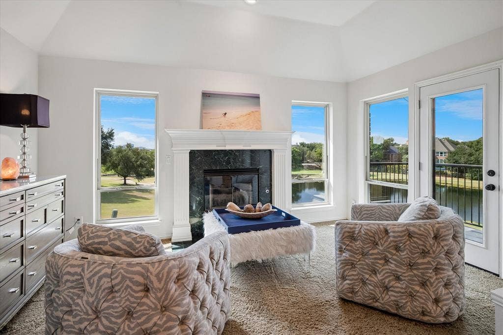 7501 Sweetgum Drive, Irving, TX 75063 Vaulted ceiling, fireplace with marble-finish surround, multiple windows, glass-paneled door, and balcony with metal railing