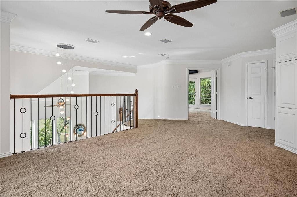 7501 Sweetgum Drive, Irving, TX 75063 Carpeted loft area featuring a wrought iron and wood banister, built-in cabinetry, and a ceiling fan