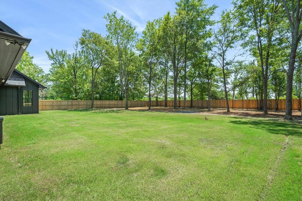 12253 Madison Xing, Bullard, TX 75757 Expansive green lawn with a privacy fence and mature trees along the perimeter