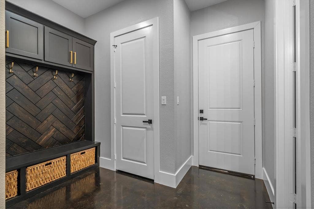 12253 Madison Xing, Bullard, TX 75757 Built-in mudroom cabinetry featuring a dark wood herringbone back panel, gold-tone hardware, and integrated storage bench with woven baskets