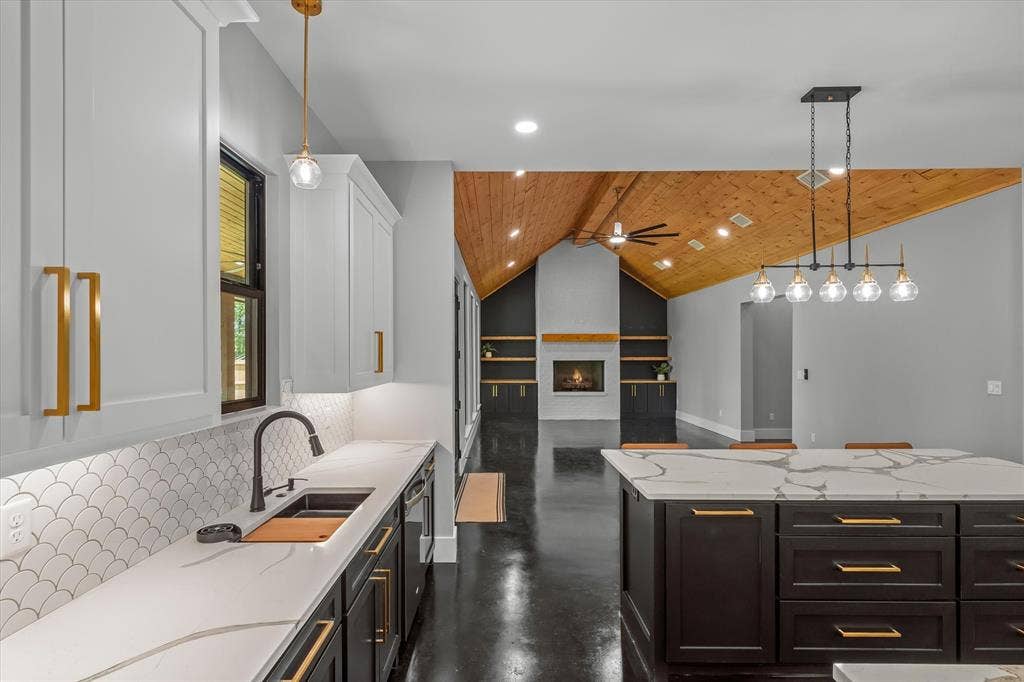 12253 Madison Xing, Bullard, TX 75757 Modern kitchen featuring white shaker upper cabinetry and dark lower cabinetry, quartz countertops with a waterfall edge, a scalloped tile backsplash, and a black sink with a matte black faucet