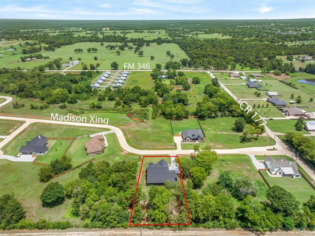 12253 Madison Xing, Bullard, TX 75757 Aerial perspective showcasing a property outlined in red, featuring a dark-roofed residence nestled among mature trees
