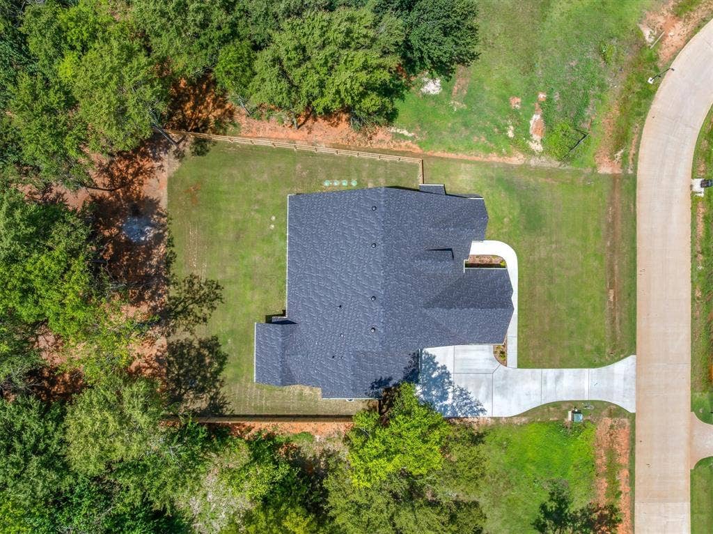 12253 Madison Xing, Bullard, TX 75757 Aerial view showcasing a newly constructed home with a dark shingle roof, concrete driveway, and expansive green lawn