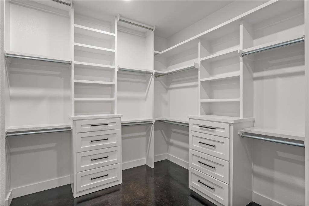 12253 Madison Xing, Bullard, TX 75757 Custom closet system featuring white cabinetry and shelving, built-in drawer units with matte black hardware, multiple hanging rods, and dark flooring