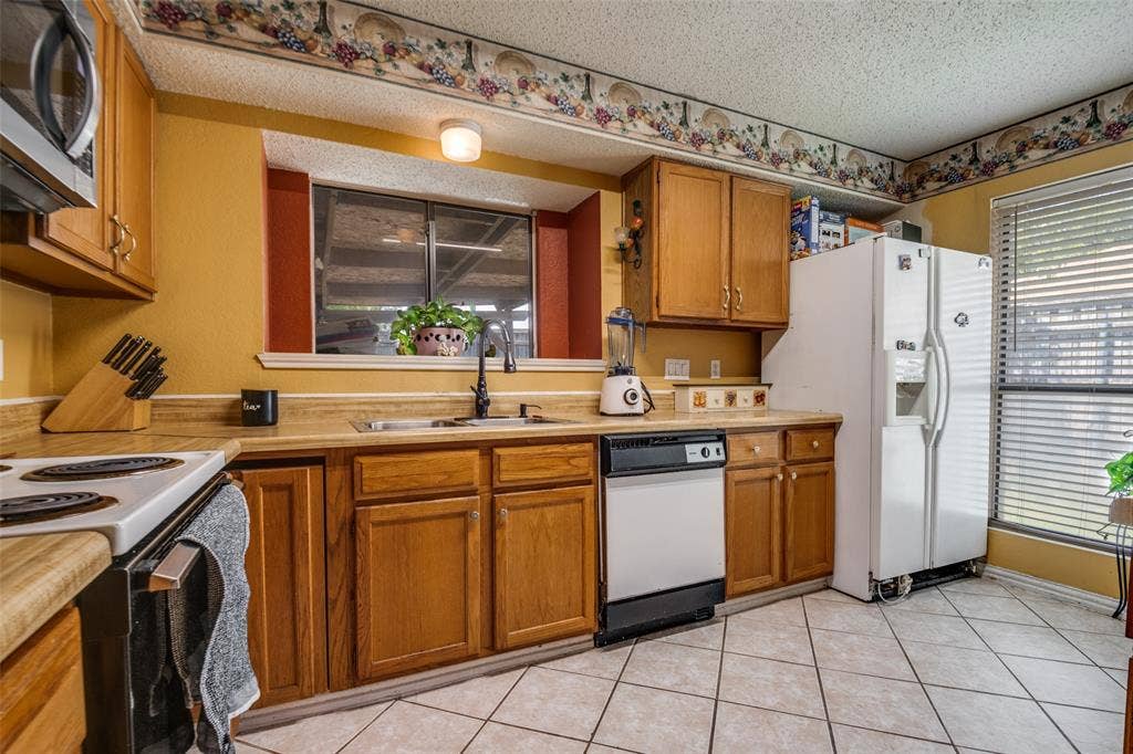Kitchen featuring wood cabinetry, laminate countertops, a built-in microwave, and tile flooring