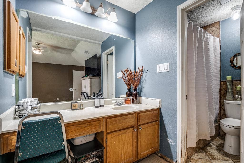Bathroom featuring a vanity with wood-finish cabinetry, a large mirror, and an integrated sink with a chrome faucet