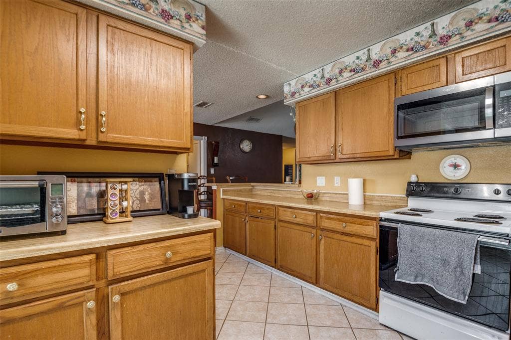 Kitchen featuring wood-finish cabinetry, light-toned countertops, and tile flooring