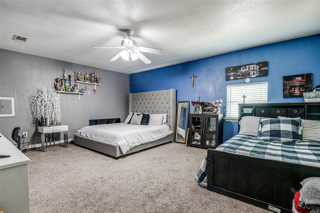 Textured carpeting throughout, ceiling fan with integrated lighting, window with blinds, and built-in shelving