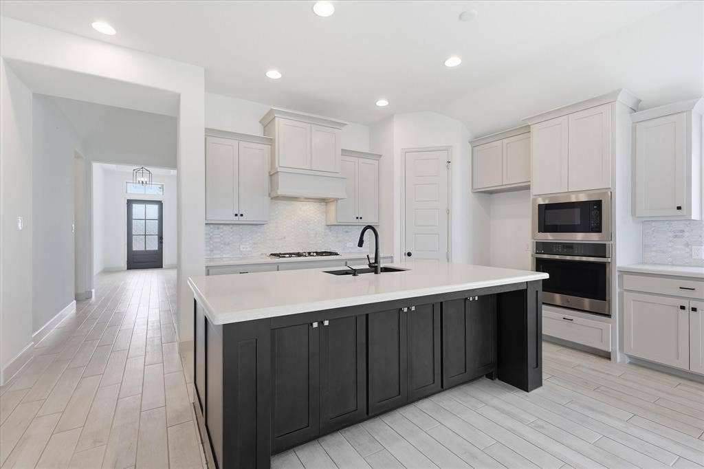 787 Cedarwood Court, Haslet, TX 76052 Modern kitchen featuring a central island with dark cabinetry, integrated sink, and white countertop