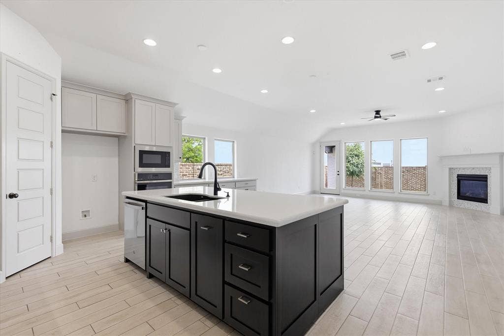 787 Cedarwood Court, Haslet, TX 76052 Kitchen island featuring a black sink and matte black faucet, complemented by light wood-finish flooring