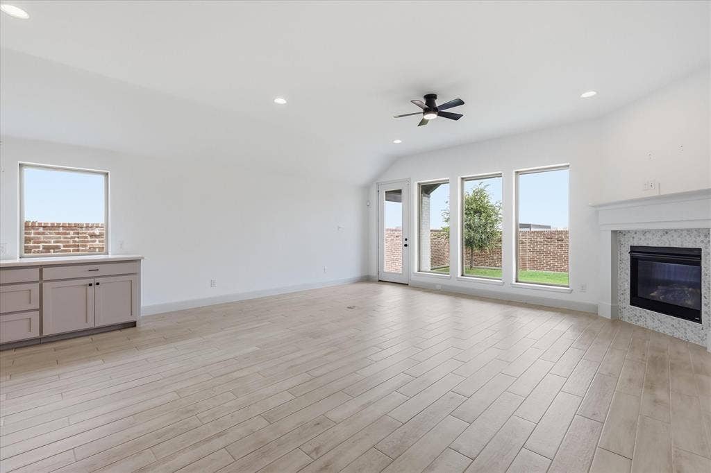 787 Cedarwood Court, Haslet, TX 76052 Spacious room featuring light wood-finish flooring, a fireplace with a textured tile surround and white mantle, and multiple large windows