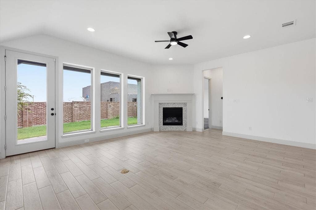 787 Cedarwood Court, Haslet, TX 76052 Spacious living area featuring light wood-finish flooring, a contemporary fireplace with a decorative mantel, and recessed lighting