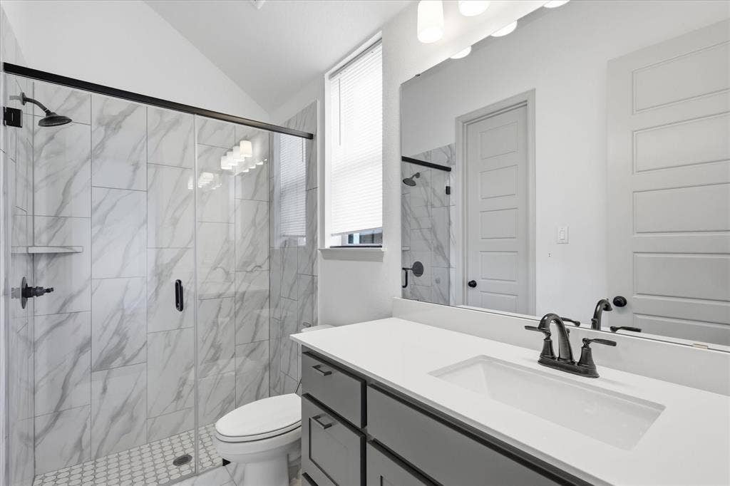 787 Cedarwood Court, Haslet, TX 76052 Bathroom featuring a walk-in shower with large format tile surround and glass enclosure, a white vanity with integrated sink, chrome-finish fixtures, and built-in vanity lighting