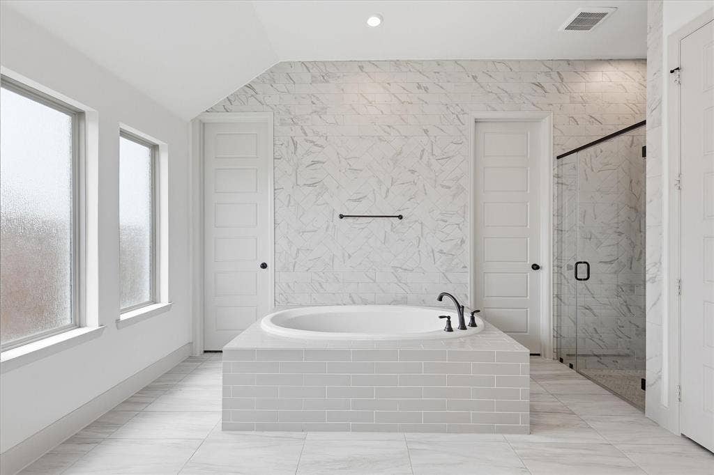 787 Cedarwood Court, Haslet, TX 76052 Built-in soaking tub with matte black fixtures, surrounded by subway tile and a marble-look tiled accent wall