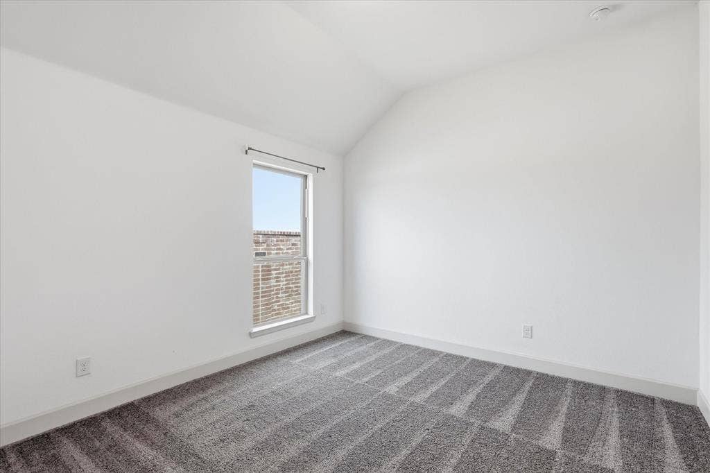 787 Cedarwood Court, Haslet, TX 76052 Room featuring a window with a brick exterior visible, clean white walls, a textured gray carpet, and a sloping ceiling line