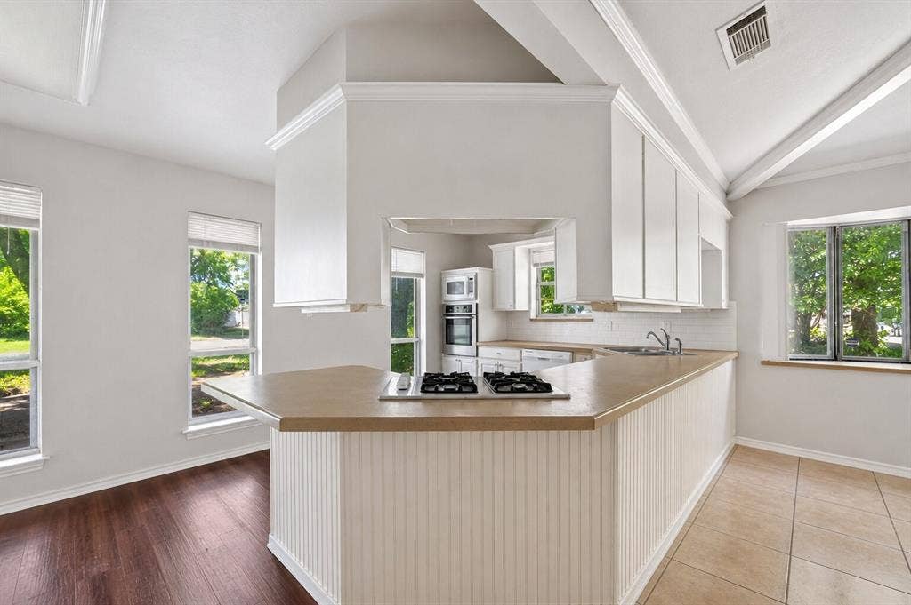 600 Terrace Drive, DeSoto, TX 75115 Kitchen featuring an extended peninsula with beadboard paneling, light-toned countertops, and a built-in gas cooktop