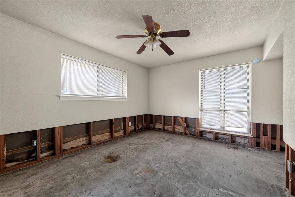 600 Terrace Drive, DeSoto, TX 75115 Room featuring two windows with horizontal blinds, a ceiling fan with light fixture, exposed wall studs, and concrete flooring