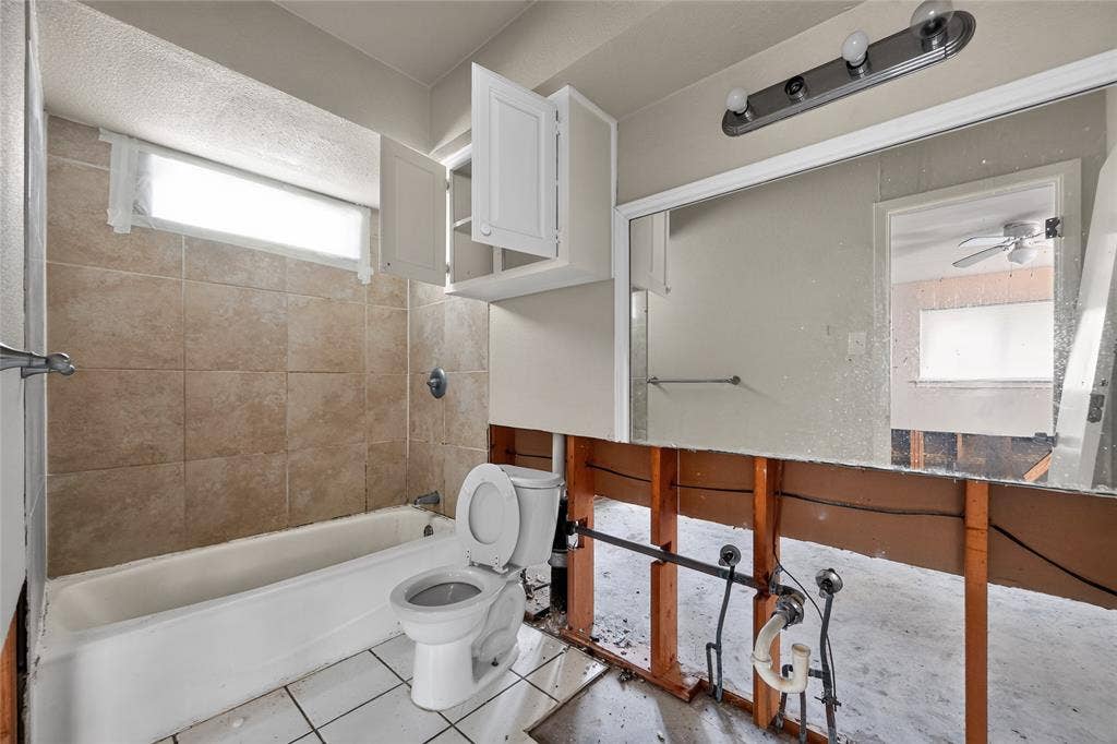600 Terrace Drive, DeSoto, TX 75115 Bathroom featuring a white bathtub, ceramic wall tiling, and a window for natural light