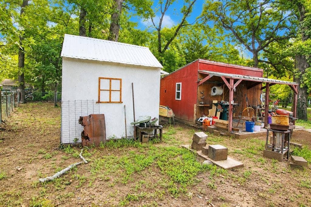 921 Crown Drive, Tool, TX 75143 Two outbuildings featuring a white shed with a window and a red shed with an open-air covered porch area