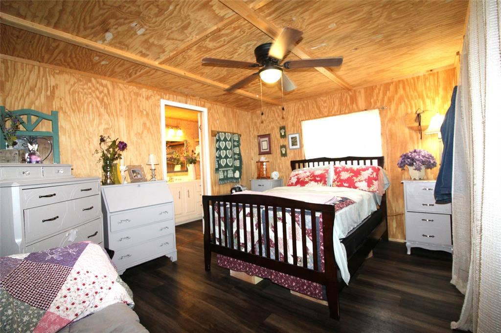 921 Crown Drive, Tool, TX 75143 Interior room featuring wood-finish walls and ceiling, dark wood-finish flooring, a ceiling fan with integrated lighting, and a white framed doorway