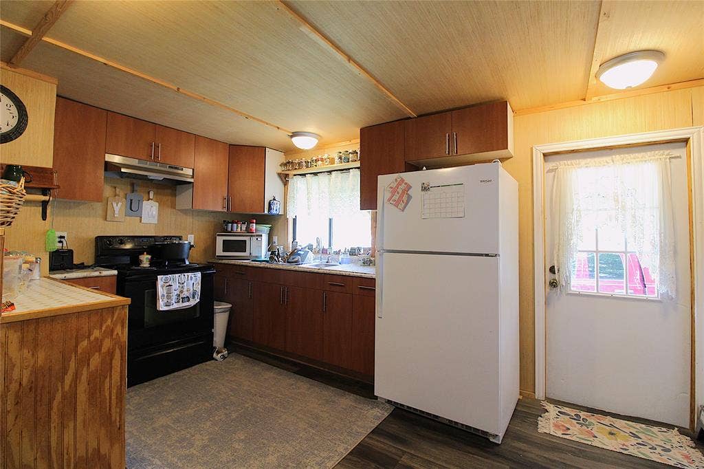 921 Crown Drive, Tool, TX 75143 Kitchen featuring wood-finish cabinetry, black electric range with overhead vent, and a white refrigerator