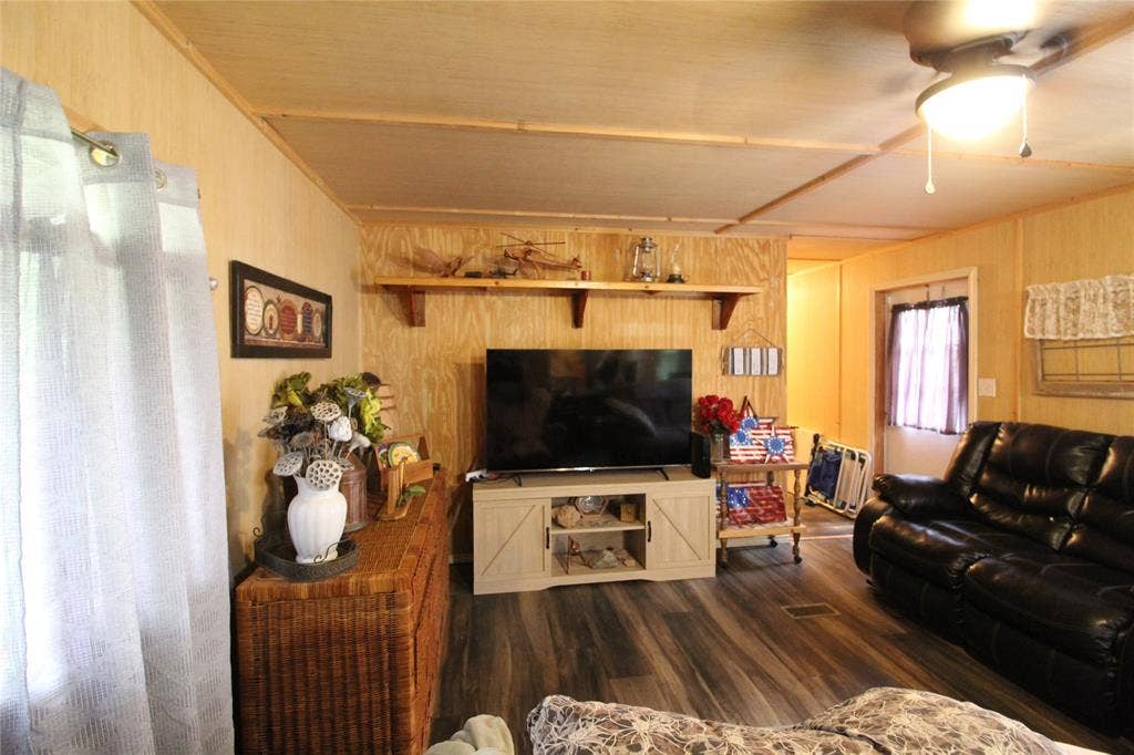 921 Crown Drive, Tool, TX 75143 Living area featuring wood-finish laminate flooring, panel walls, and a ceiling fan with integrated lighting