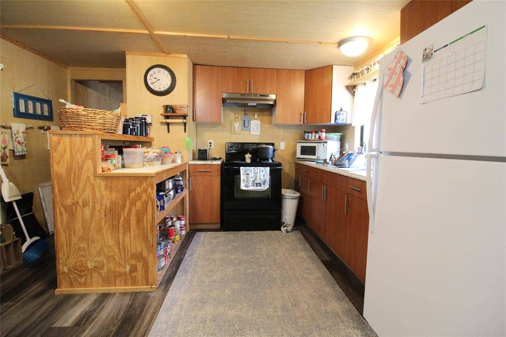 921 Crown Drive, Tool, TX 75143 Kitchen featuring wood-finish flooring, wood cabinetry with brushed nickel hardware, light-toned countertops, and a full-size white refrigerator