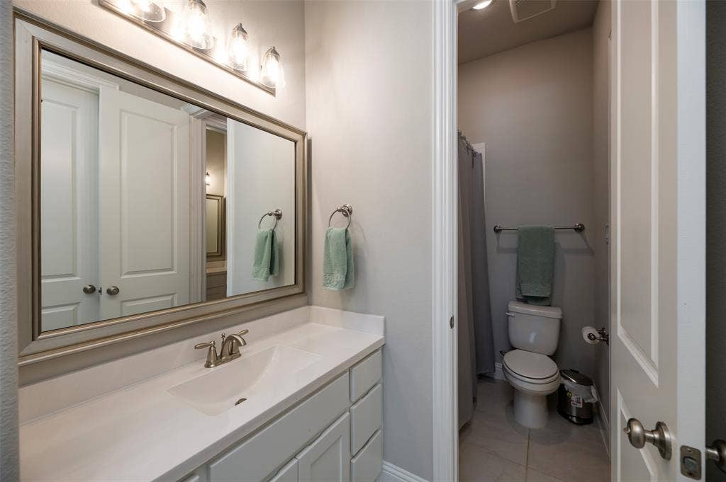 1109 10th Street, Argyle, TX 76226 Bathroom vanity featuring a single integrated sink, light-toned countertop, and white cabinetry- jack and jill bathroom