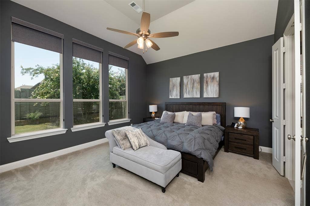 1109 10th Street, Argyle, TX 76226 Vaulted ceiling room featuring three large windows, a ceiling fan with integrated lighting, soft carpet flooring, and bi-fold doors