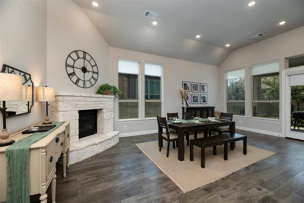 1109 10th Street, Argyle, TX 76226 Vaulted ceiling room featuring a stone-clad fireplace, wood-finish flooring, recessed lighting, and multiple windows