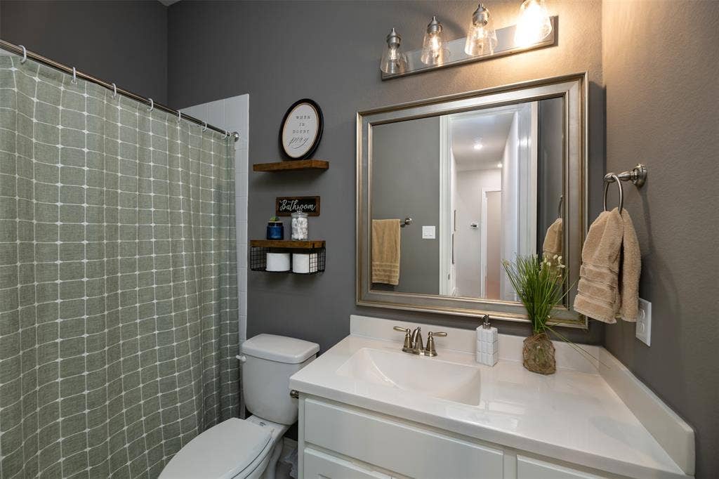 1109 10th Street, Argyle, TX 76226 Bathroom featuring a single vanity with an integrated sink, polished chrome faucet, and a framed mirror