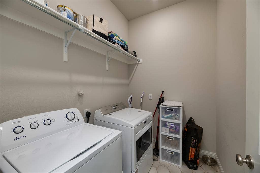 1109 10th Street, Argyle, TX 76226 Dedicated laundry area featuring a full-size washer and dryer, upper storage shelving, and hexagonal floor tiling