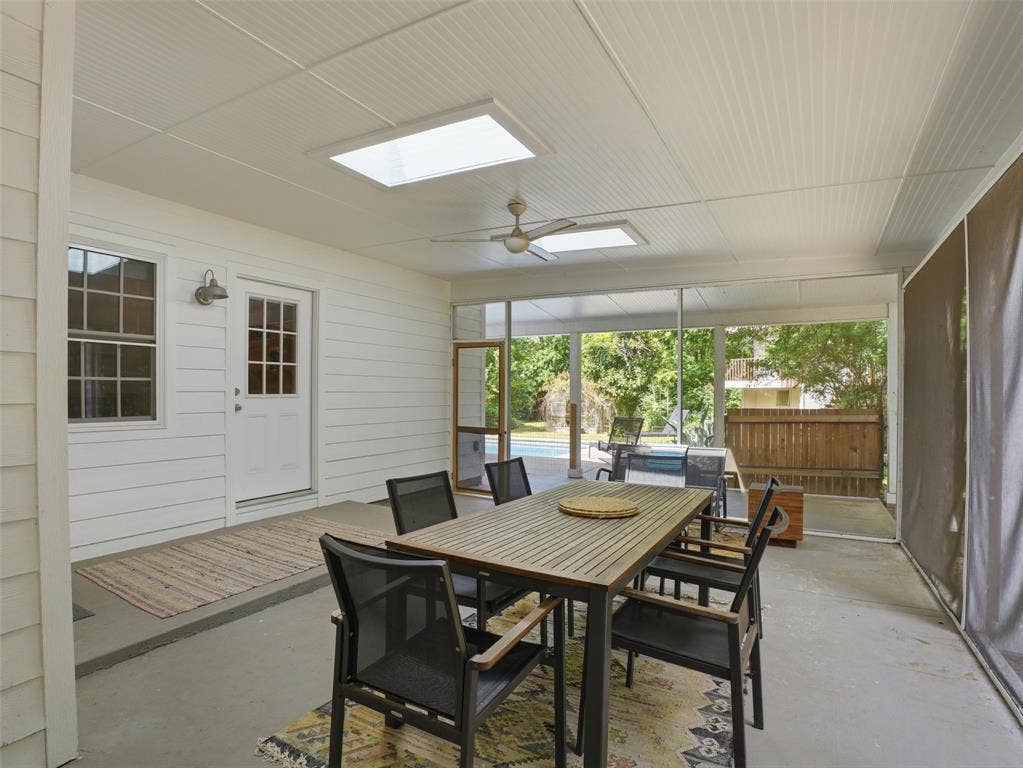 Screened-in porch featuring a beadboard ceiling with two skylights and a ceiling fan