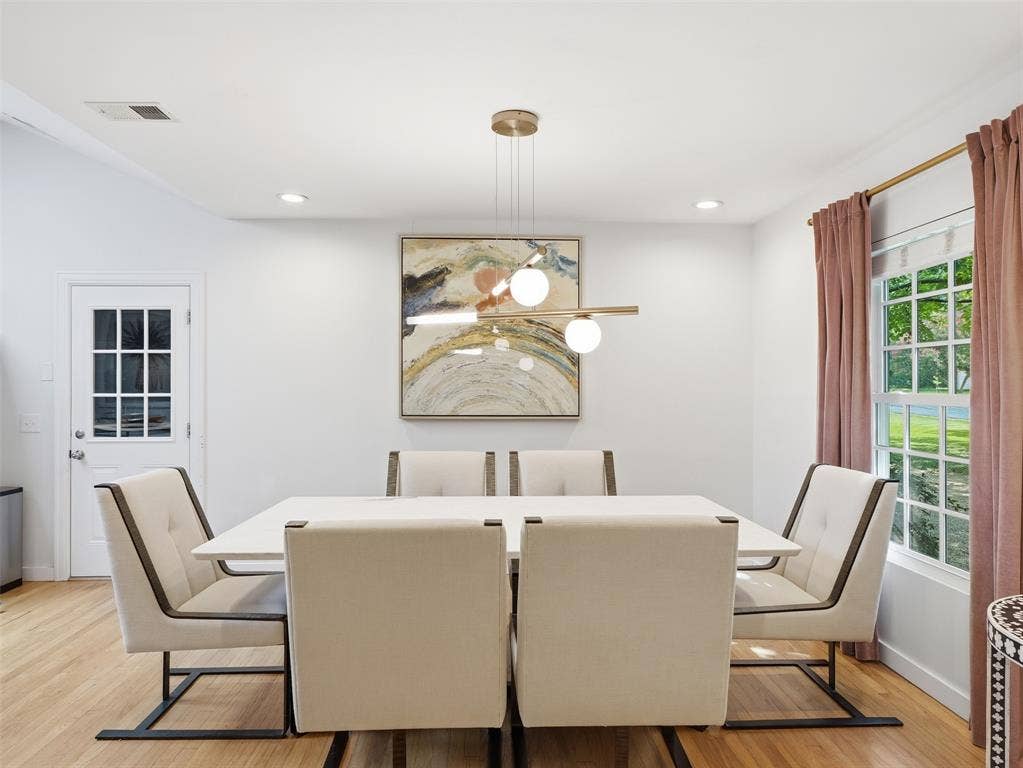 Dining space featuring light wood-finish flooring, a contemporary linear chandelier with globe lights, and recessed ceiling lighting
