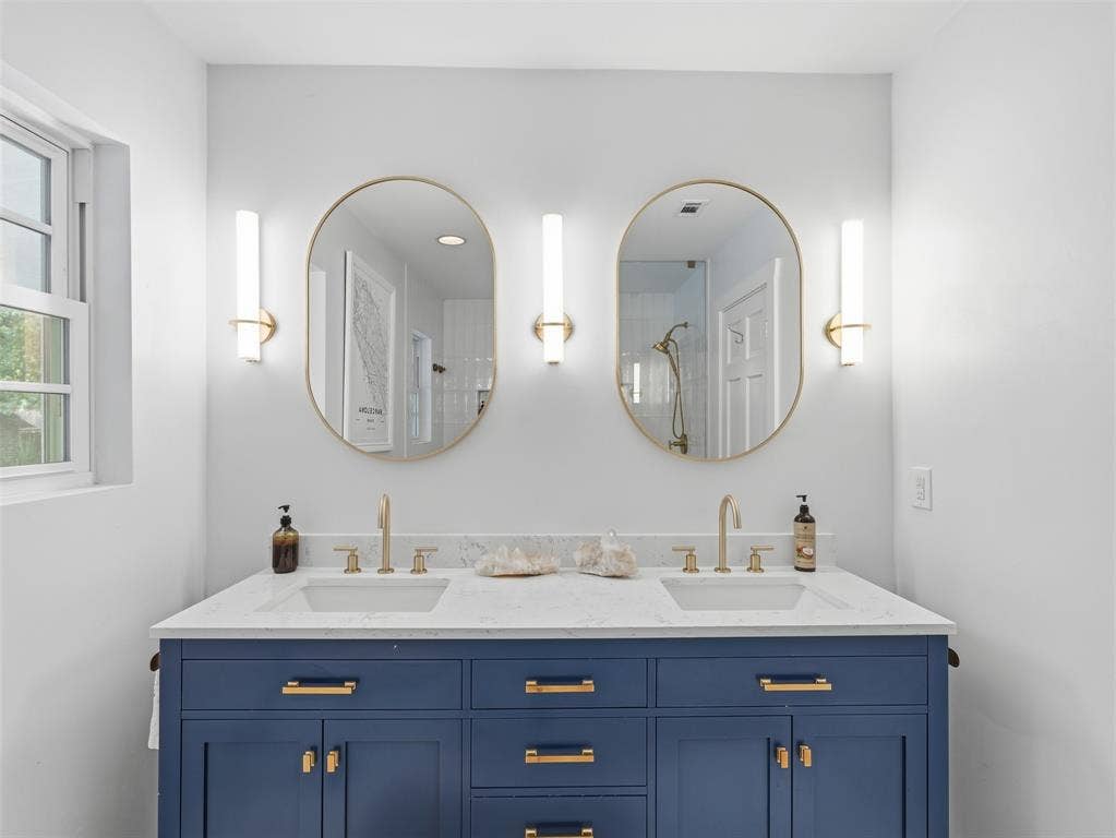 Dual vanity with a deep blue base cabinetry and gold-tone hardware