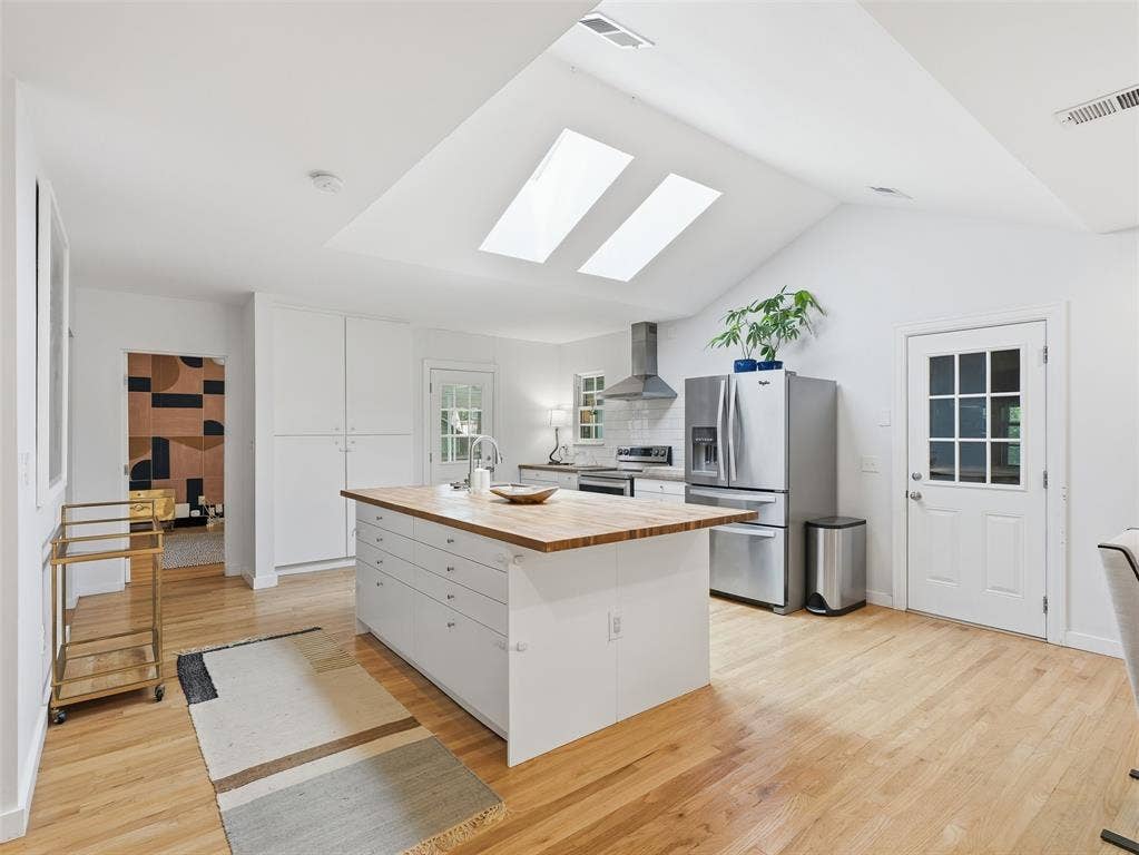 Vaulted ceilings with two skylights illuminate the open-concept kitchen, featuring light wood-finish flooring