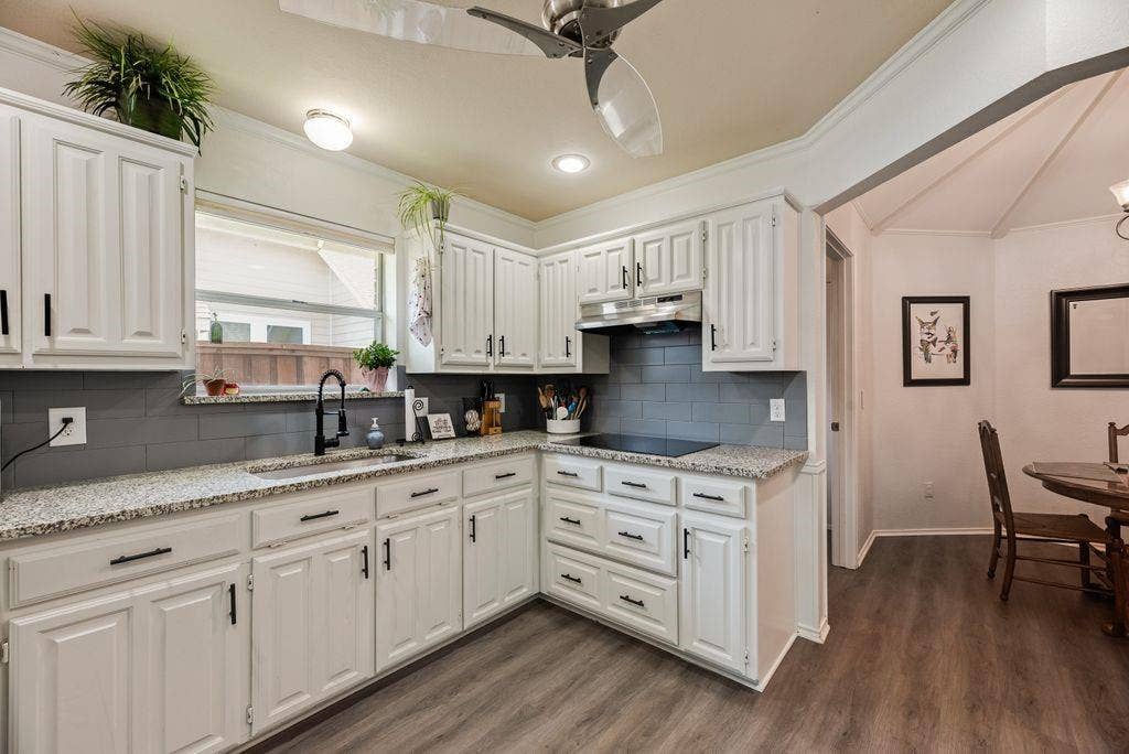 419 N Winding Oaks Drive, Wylie, TX 75098 Kitchen featuring white cabinetry, speckled countertops, gray subway tile backsplash, and wood-finish flooring