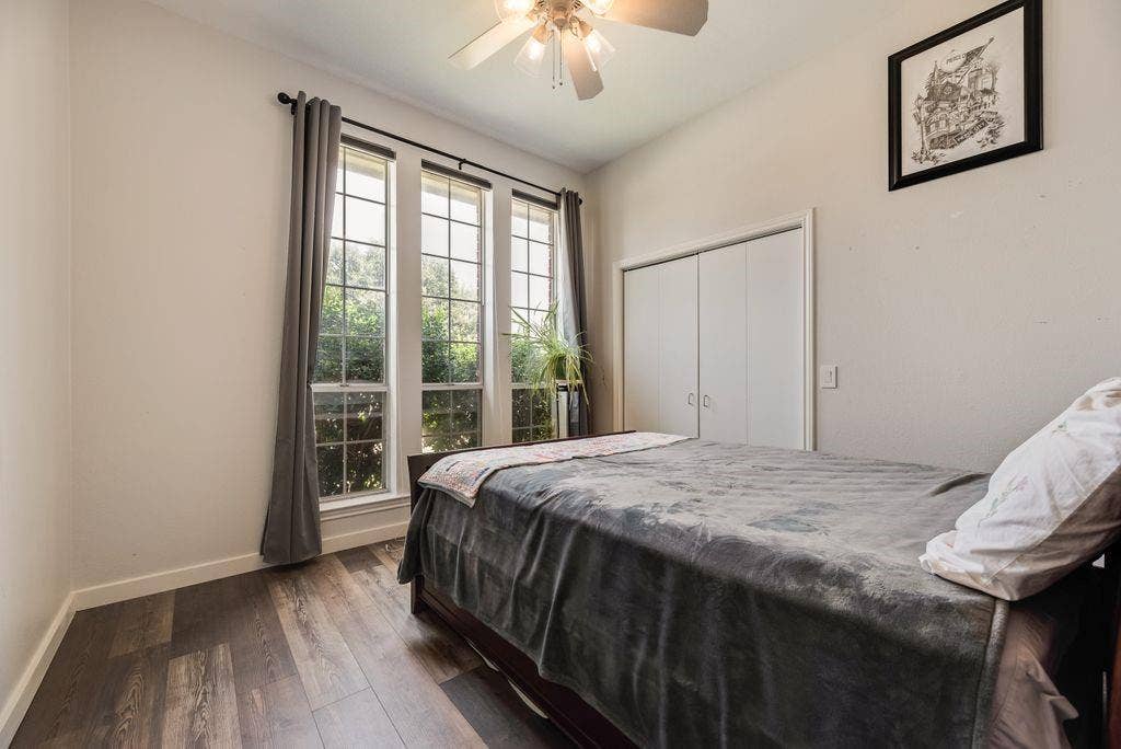 419 N Winding Oaks Drive, Wylie, TX 75098 Room featuring wood-finish flooring, three vertical windows with dark rods, a ceiling fan, and white bi-fold closet doors