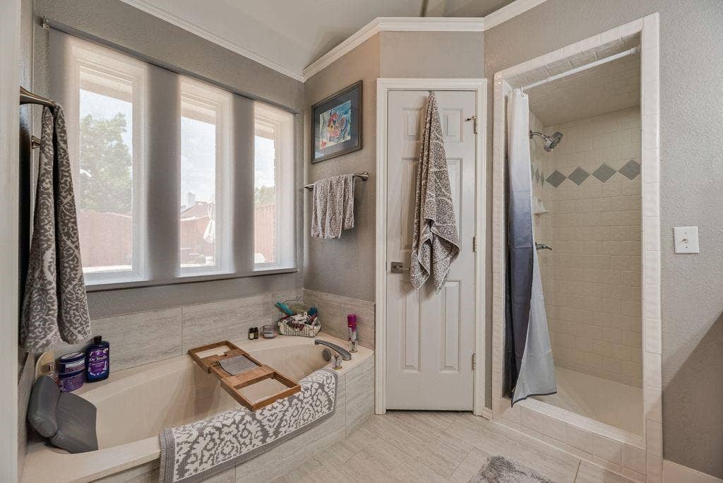 419 N Winding Oaks Drive, Wylie, TX 75098 Soaking tub with a tiled surround, three large windows, and a separate shower with a decorative tile band
