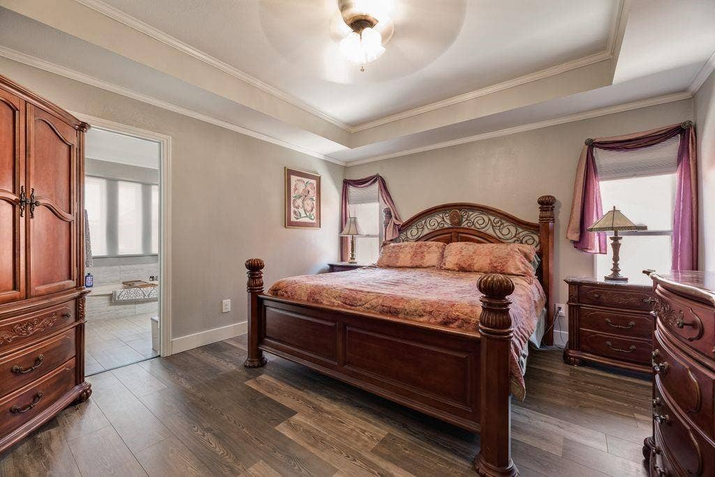 419 N Winding Oaks Drive, Wylie, TX 75098 Bedroom featuring wood-finish flooring, tray ceiling with fan, and crown molding