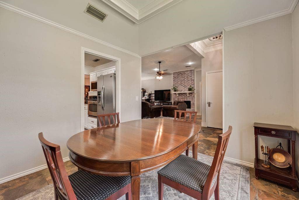 419 N Winding Oaks Drive, Wylie, TX 75098 Dining area featuring crown molding and an open pass-through to a living space with a brick-surround fireplace